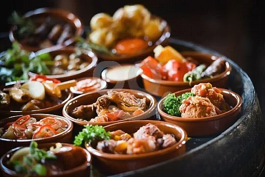 A dozen tapas in small earthenware dishes set out on the top of a barrel