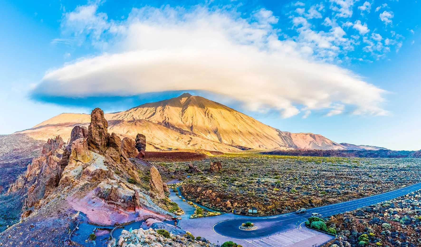 Mount Teide under a long lenticular cloud, with the rock pinnacles of the Roques de García in the foreground