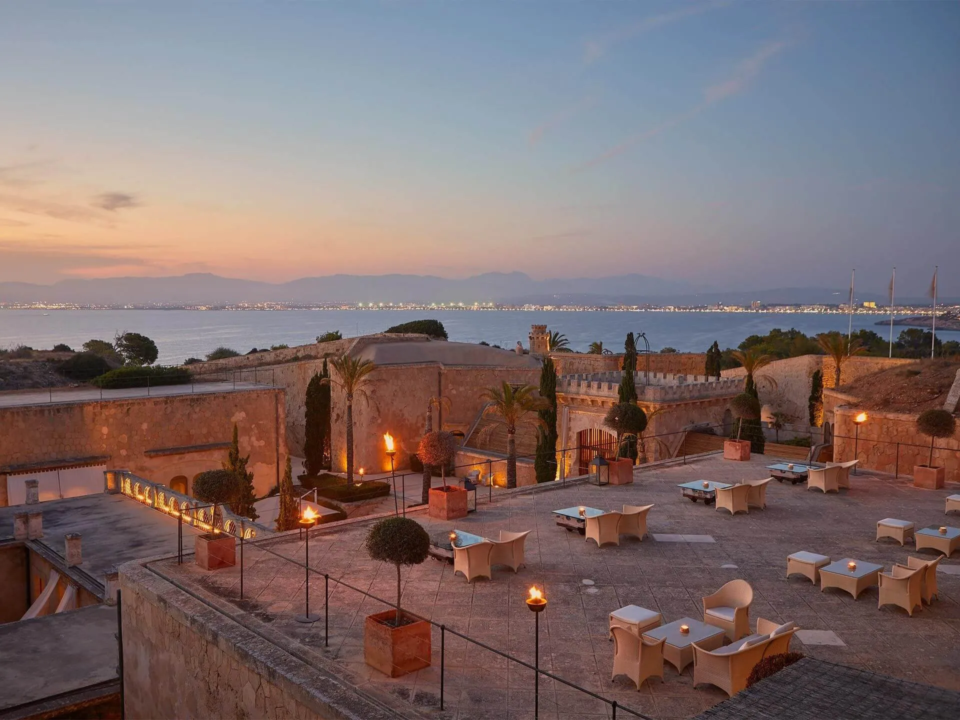 The Cap Rocat fortress at dusk, its terrace lit by torches and candles above the Bay of Palma