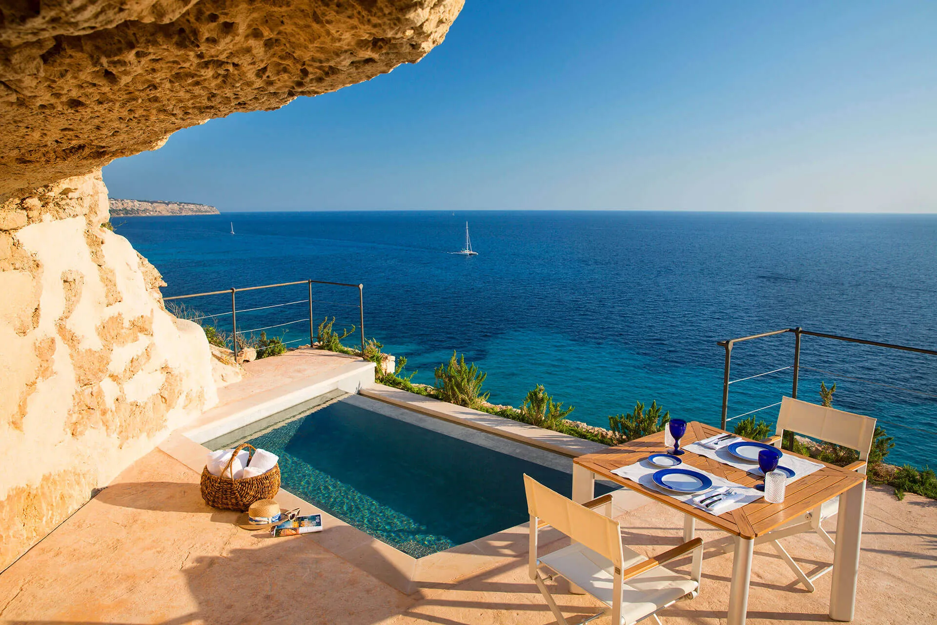 A Sentinels terrace at Cap Rocat: a plunge pool under an overhang of rock, a table laid for two and the open sea beyond