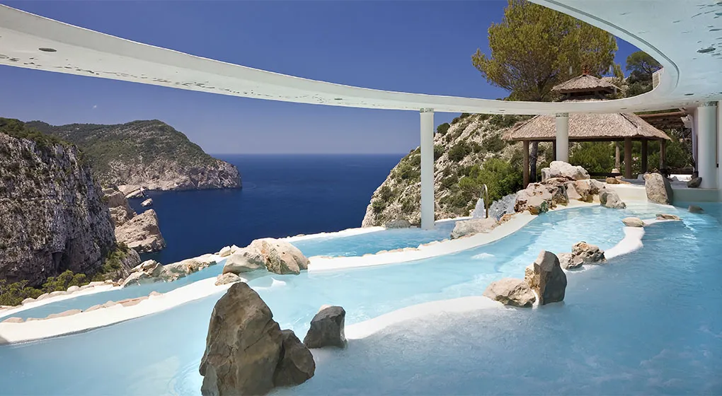 The Cascadas Suspendidas: pale pools set with boulders under a curving white canopy, above the cliffs and the sea