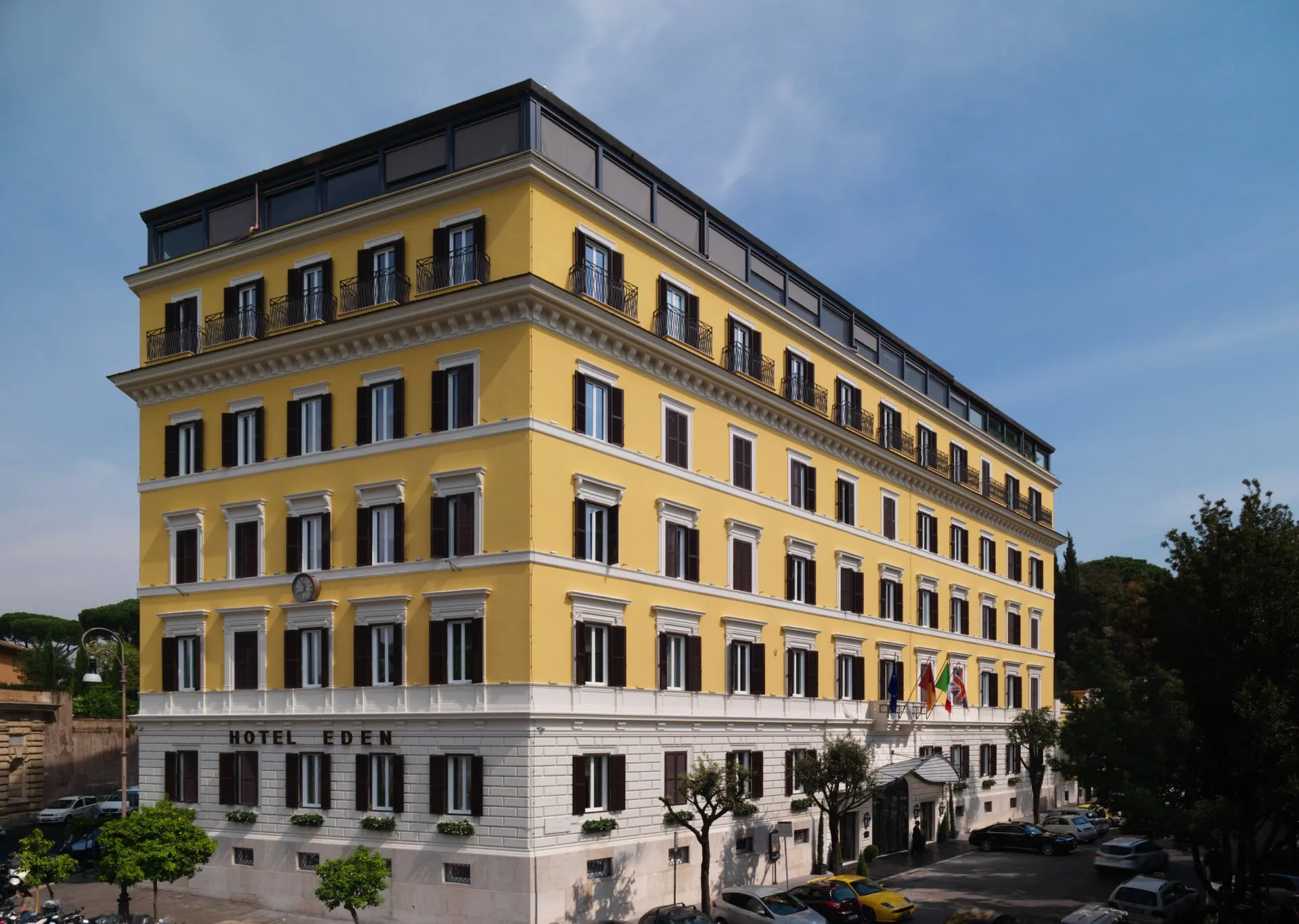 The street façade of Hotel Eden from the corner of Via Ludovisi, its flags and clock above the entrance