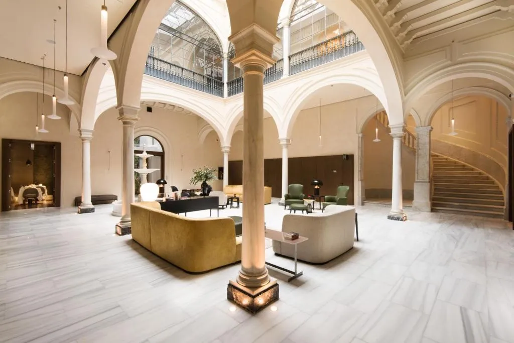 Lobby of Hotel Mercer Sevilla, with stone arches and a central fountain