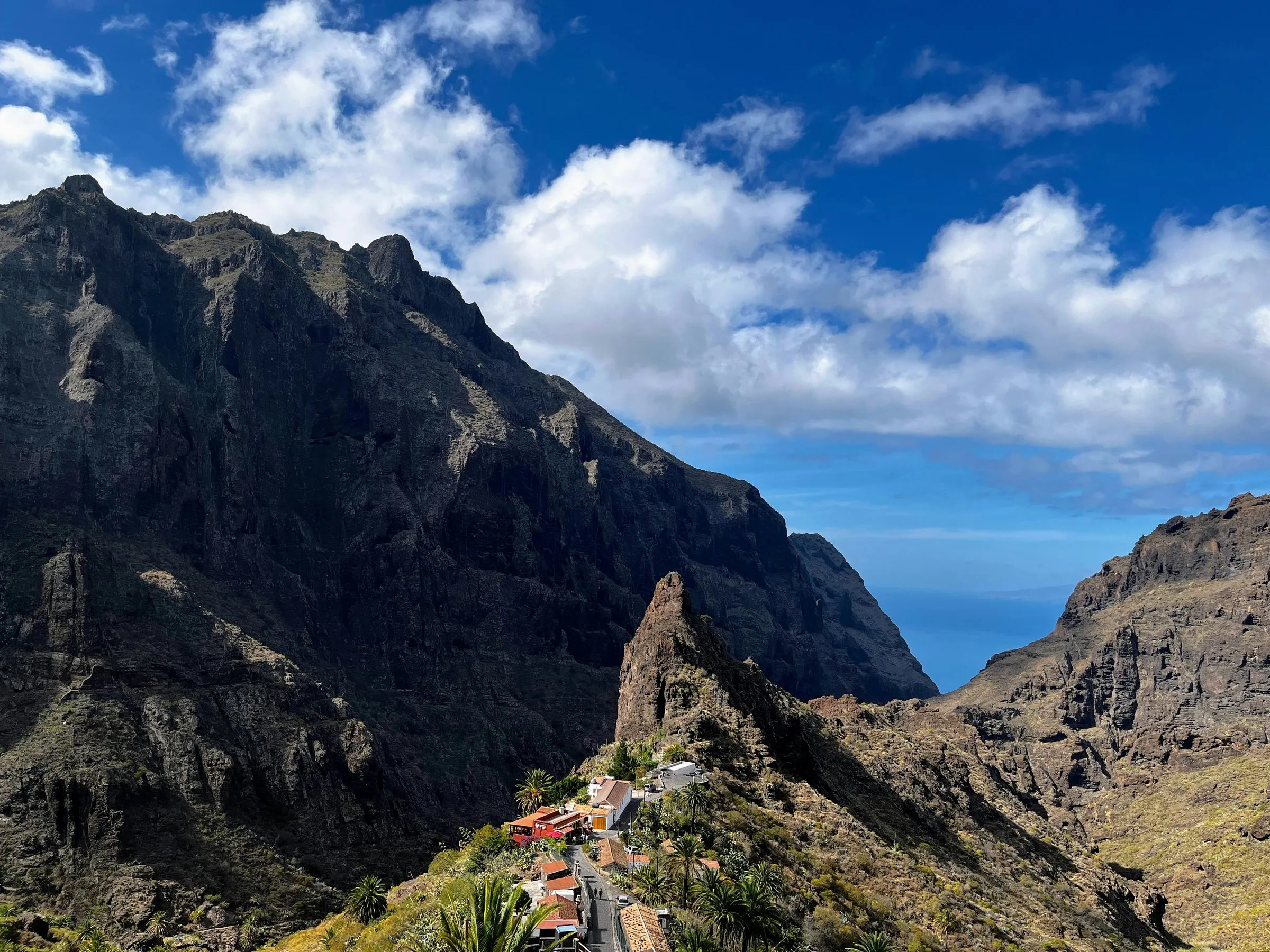 The red-roofed houses of Masca on a narrow ridge below the dark cliffs of the Teno mountains, the sea just visible through the mouth of the gorge