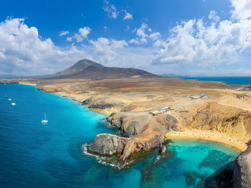 The Papagayo coast from the air, yachts anchored off small sandy coves below a brown volcanic headland