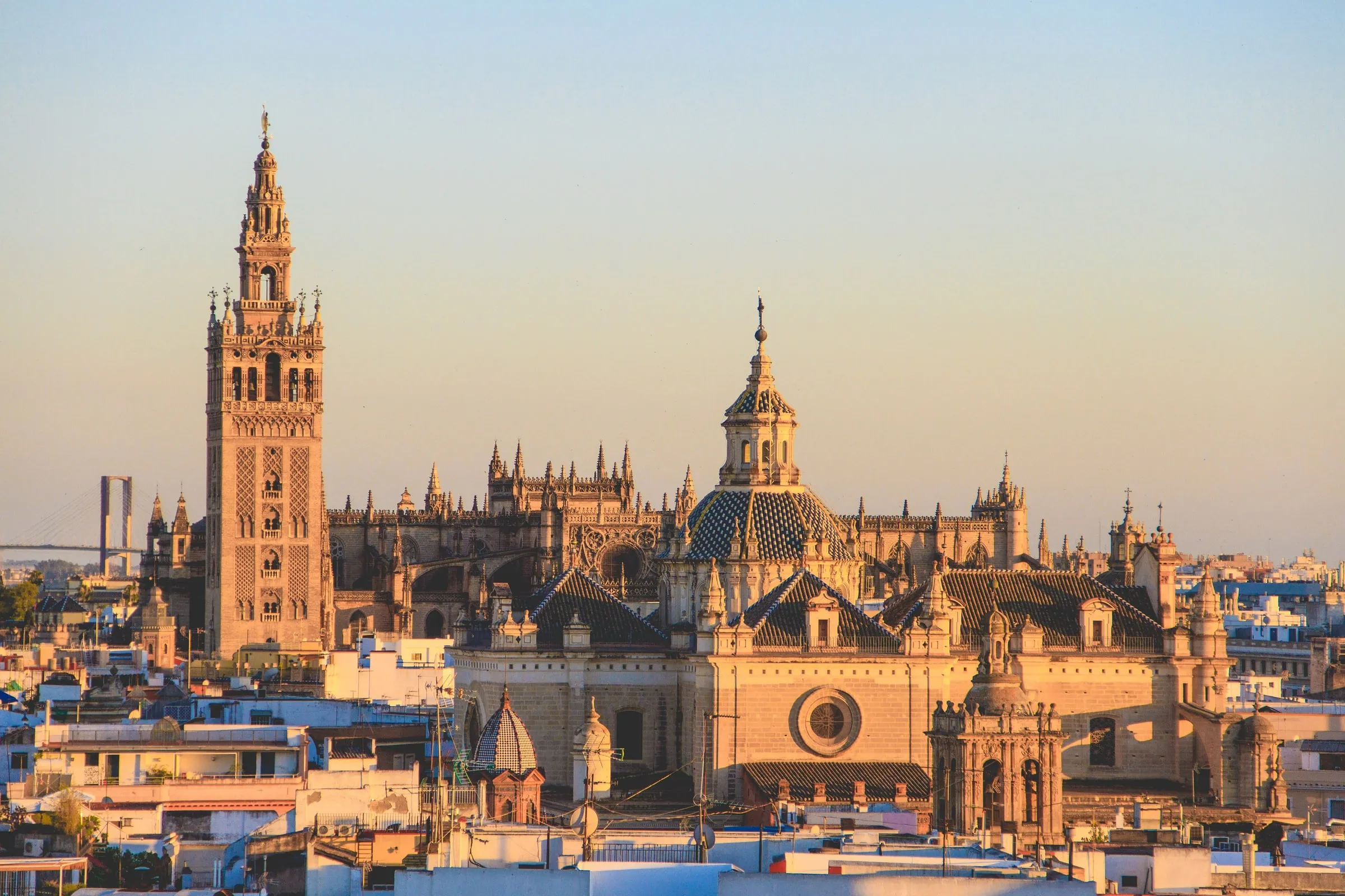 The Giralda bell tower and Seville Cathedral rising above the city's rooftops in golden light