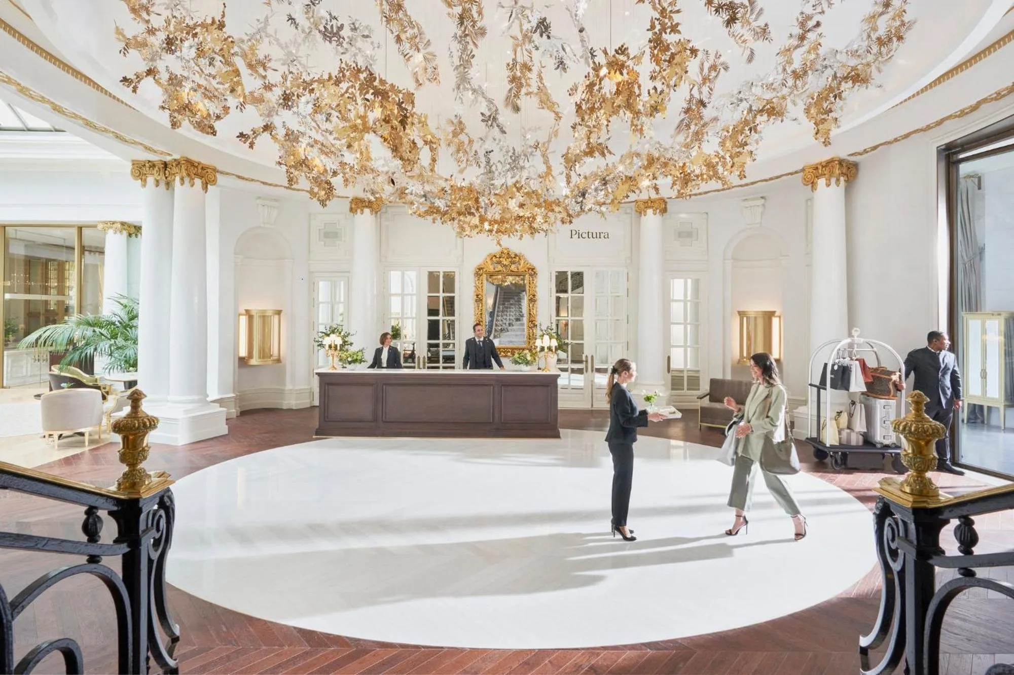 The round entrance hall of the Mandarin Oriental Ritz, with white columns and a ceiling hung with gold leaves