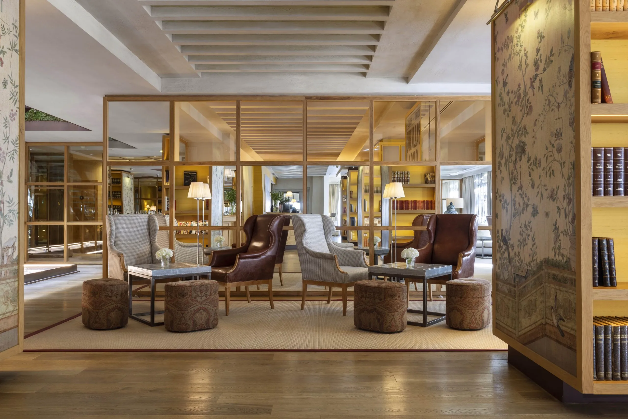 The lobby at Urso, with wing chairs and leather armchairs before glazed oak partitions and shelves of books